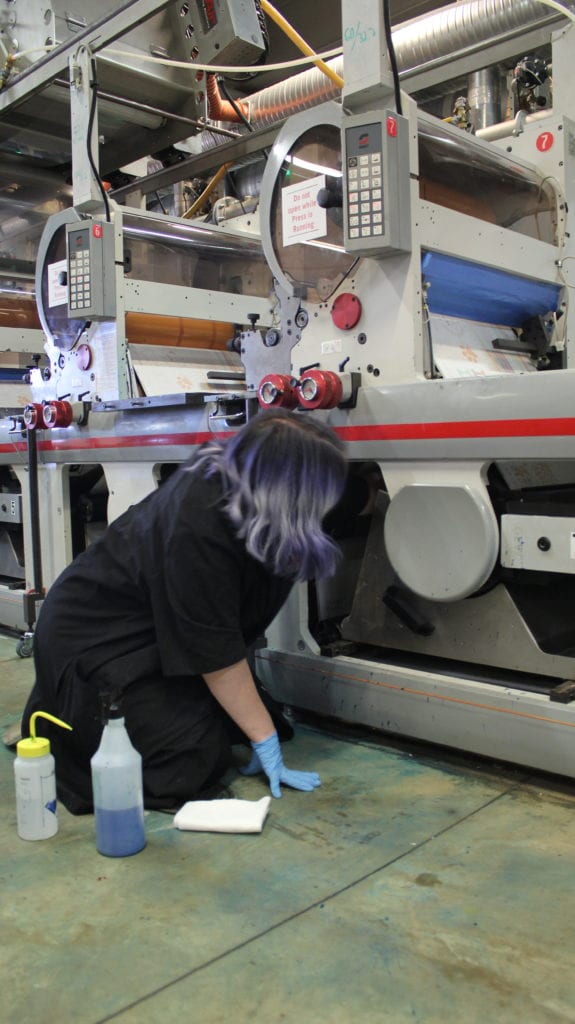 A woman works on a large piece of printing machinery.