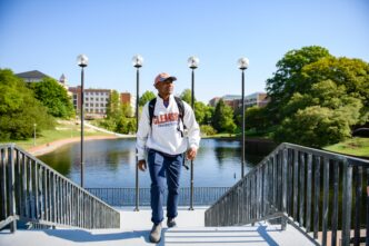 Man in Clemson sweatshirt walks up stairs in front of reflection pond