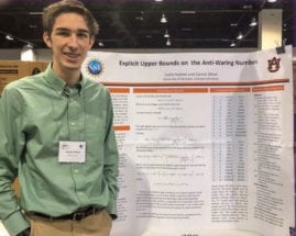 Man wearing green shirt posing in front of a research poster