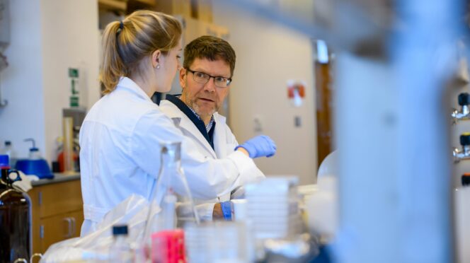 Man in lab coat talking to woman in lab coat in a lab