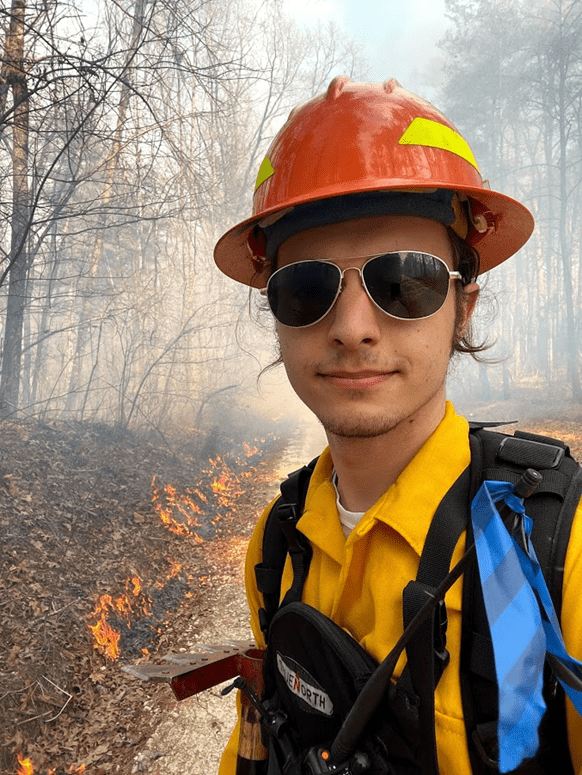 carson wearing a fire hat and fighting a wildland fire with Fire Tigers