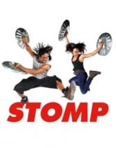 Two dancers from Stomp hold trash cans lids and jump in the air. 