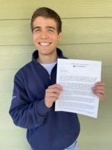 Evan Patrohay holding an acceptance letter proudly. 