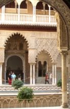 Four people take in the Alcazar Palace's Spanish architecture. 