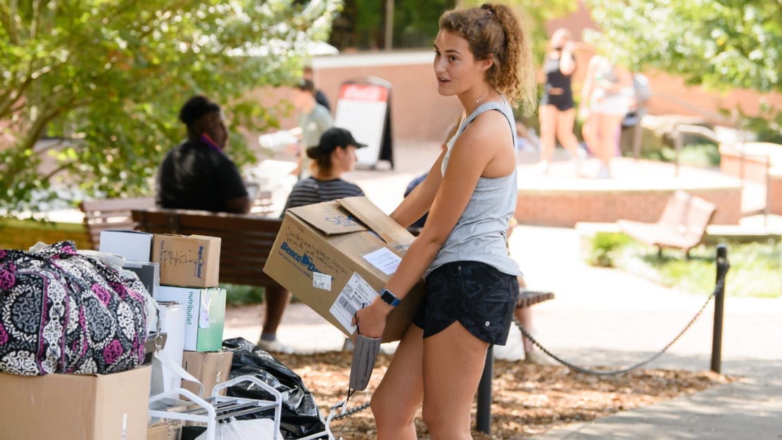A student carries a cardboard box during move-in on campus in 2020