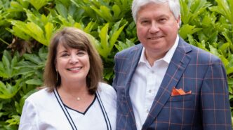 Laura and Bill Pelham standing in front of a bush.