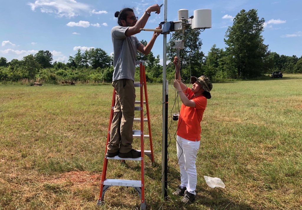 Clemson researcher Hehe Wang and graduate student Milan Panth install a weather station on a peach farm in Georgia for bacterial spot research.