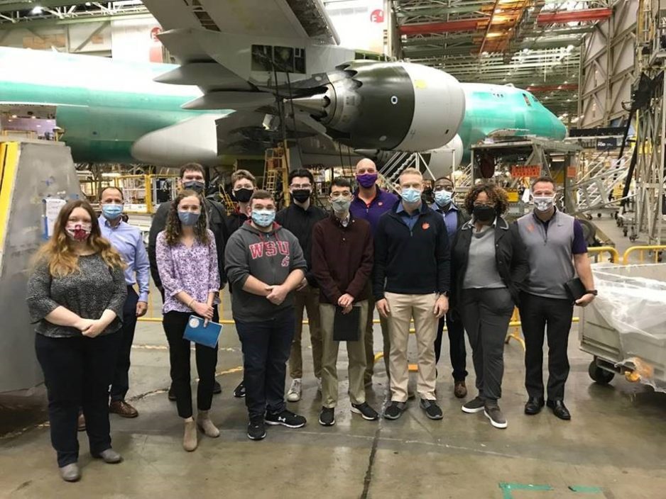 Students and faculty standing by an airplane being built in the Boeing Washington manufacturing facility.