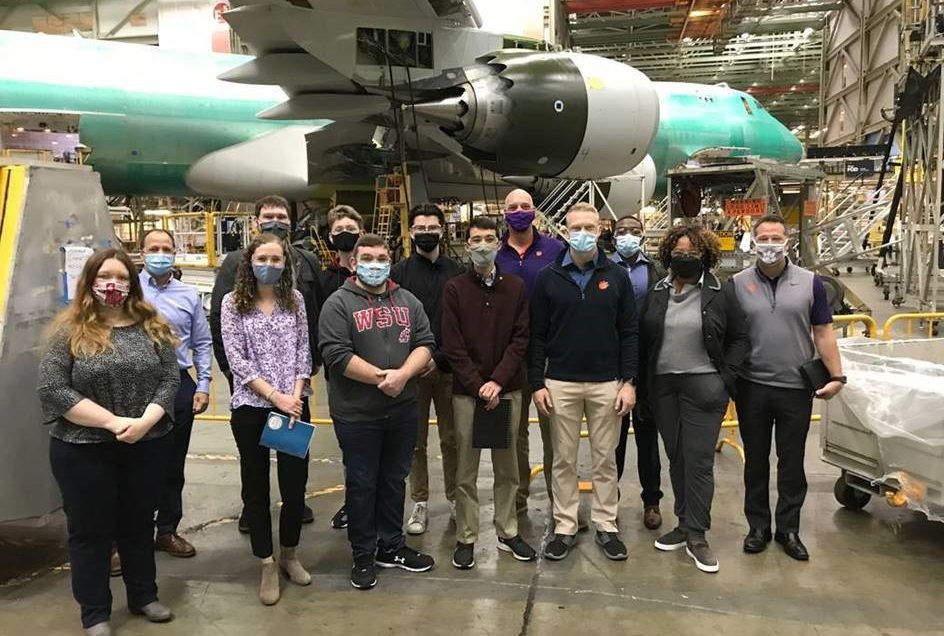Students and faculty standing by an airplane being built in the Boeing Washington manufacturing facility.