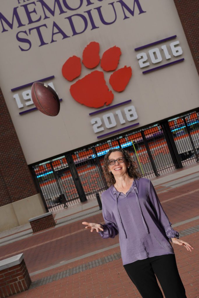 woman in front of Memorial Stadium tossing a football in the air