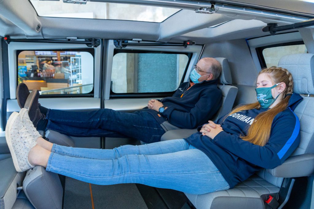 Two people lounge with their feet up in the spacious interior of the vehicle. 