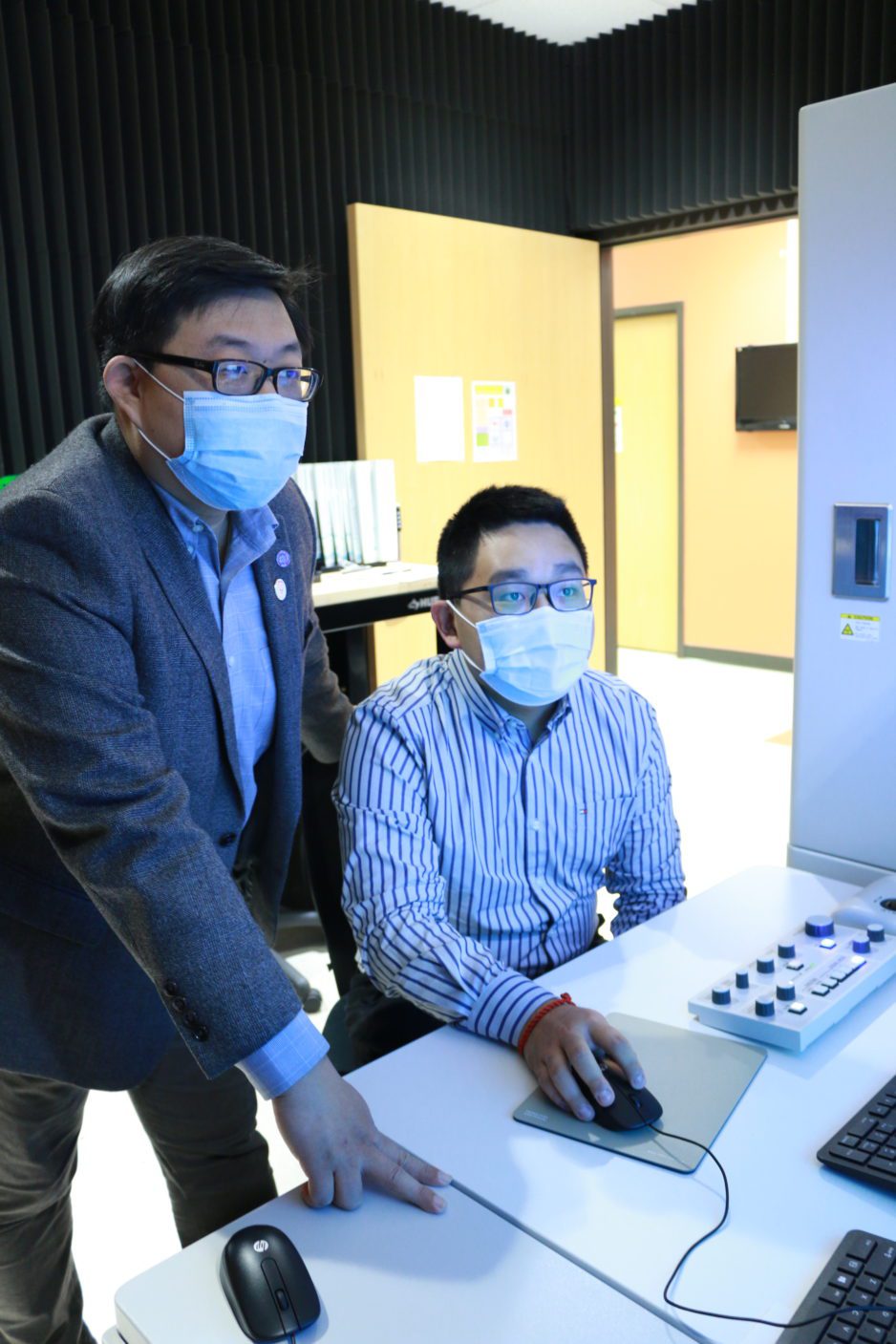 PhD student Hongkui Zheng, at right, works with faculty advisory Kai He in a microscope lab.