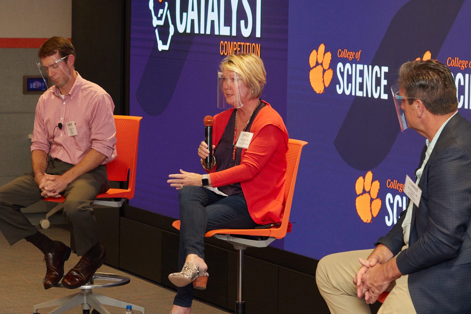 Three people sitting in tall orange chairs ion stage at College of Science's Catalyst Competition kickoff event.
