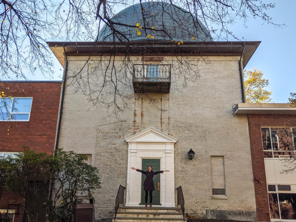 Jordan Eagle standing in front of the doors to the Harvard Smithsonian Astrophysics Center's observatory