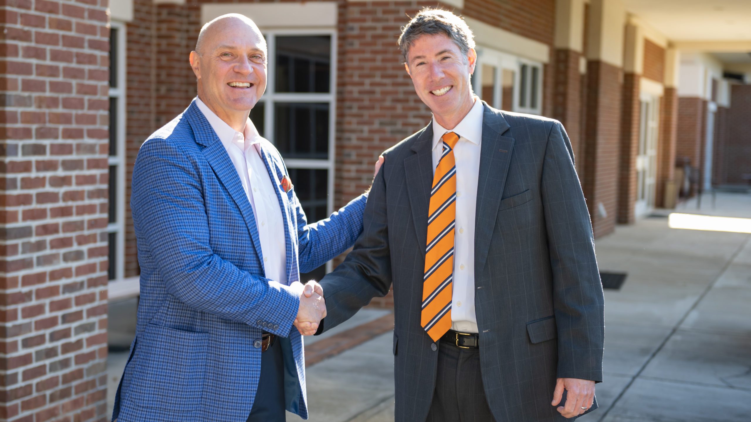 Jim Clements and Robert Halfacre share a handshake outside of the Madren Conference Center in April 2022