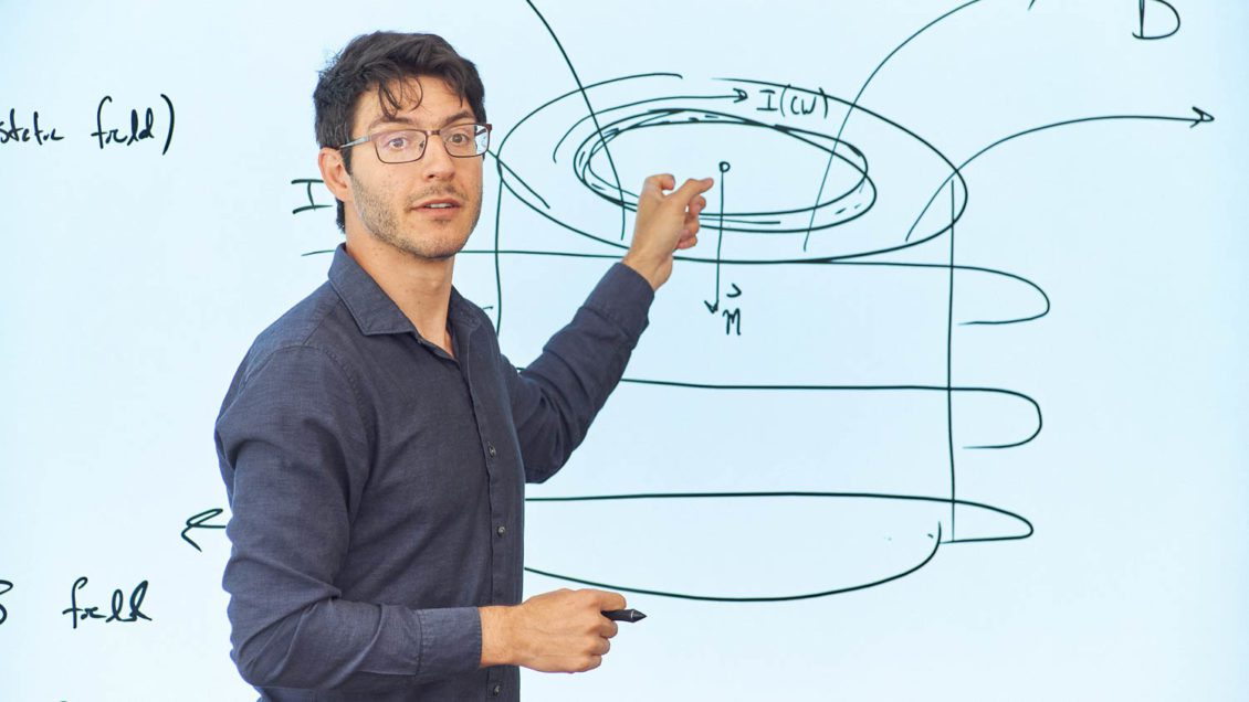 Jonathan Zrake of the Department of Physics and Astronomy, points to a drawing on a whiteboard