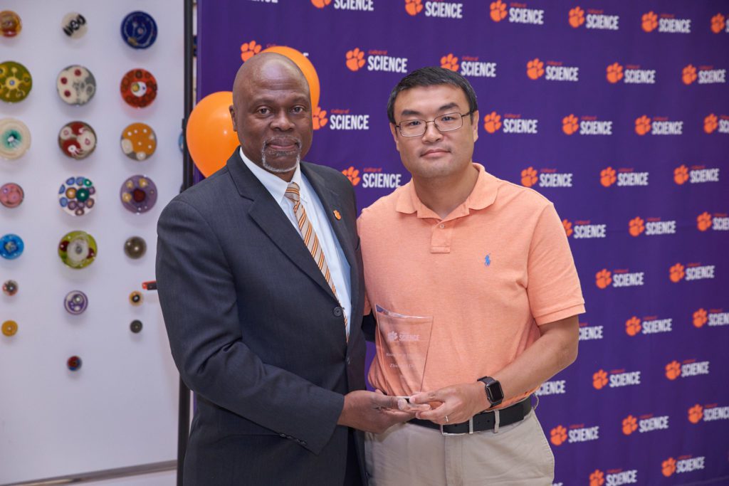 College of Science associate dean Calvin Williams and Rising Stra in Discovery Award recipient Zhicheng Dou pose with award in front of a College of Science banner.