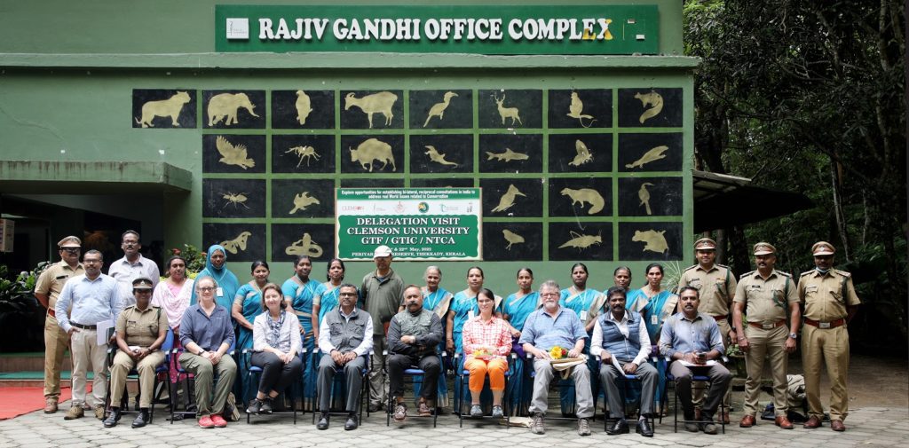 A group of people pose for a picture outside a building reading "Rajiv Gandhi Office Complex."