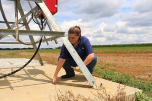 Clemson undergraduate student Anna Moore checks to be sure a center pivot irrigation system at the Simpson Research Farm is properly grounded.