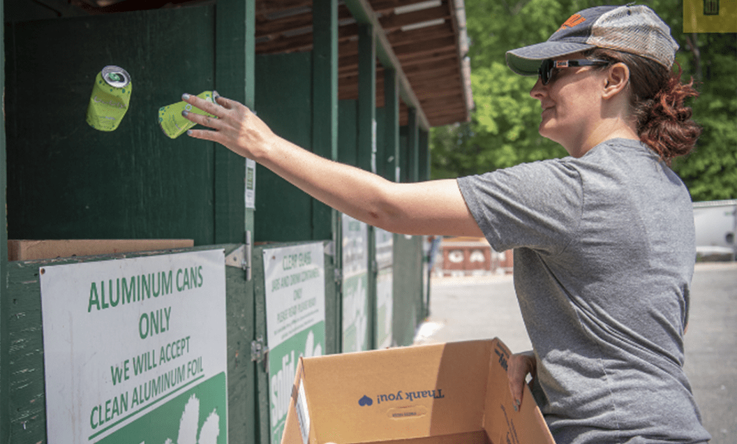 Employee putting aluminum cans in a recycle bin