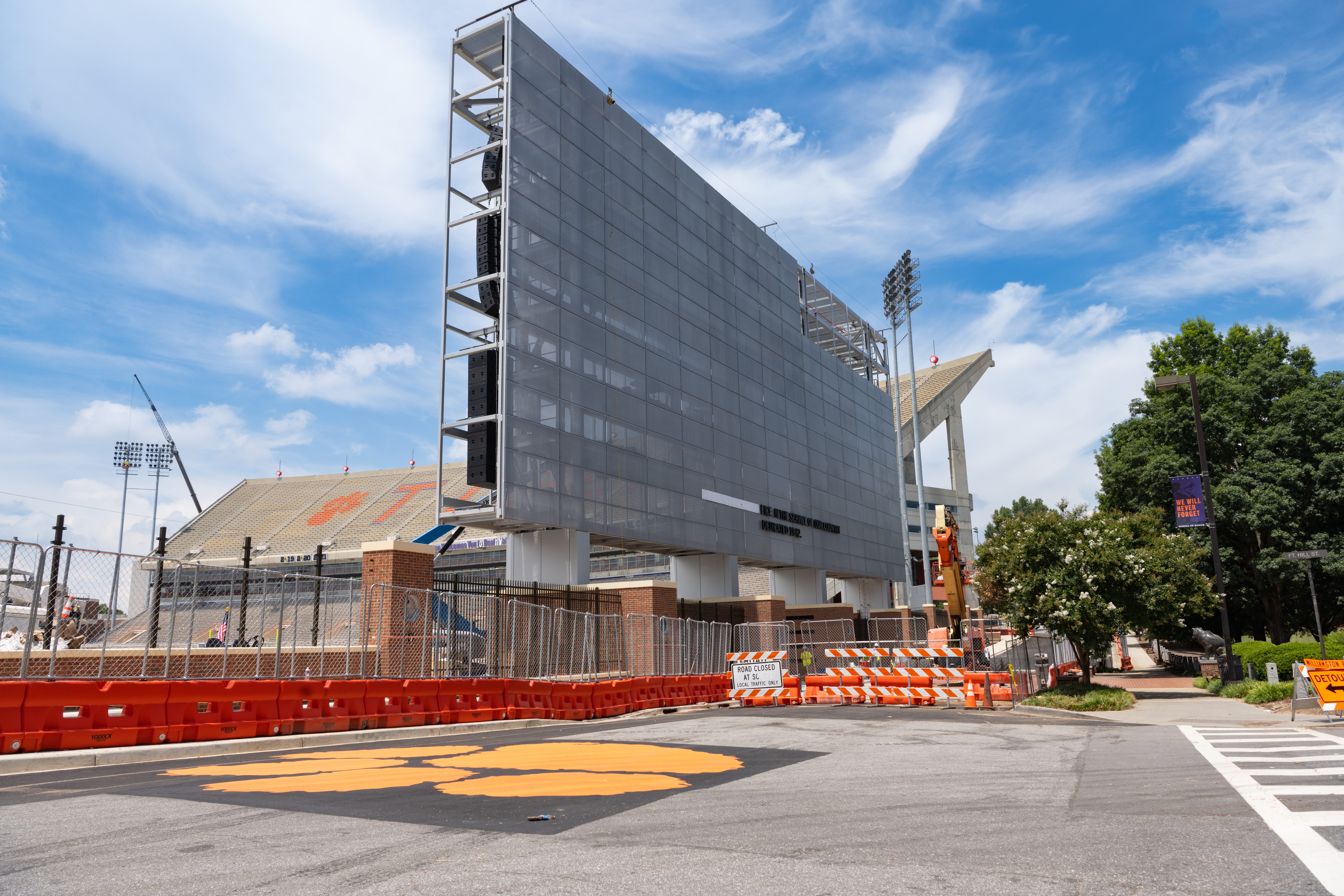 An under-construction video board in Memorial Stadium is positioned near the road painted with an orange Tiger Paw.