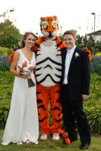 Woman in wedding dress and man in tuxedo pose with the Clemson Tiger.