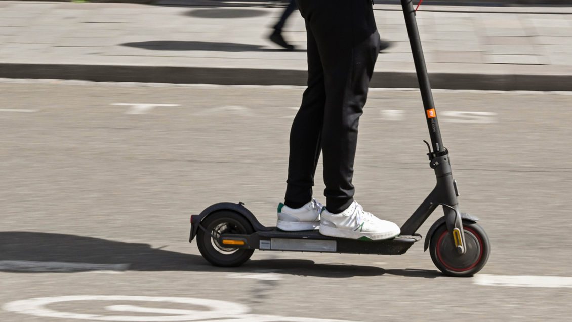 Person riding an electric scooter with blurred motion.