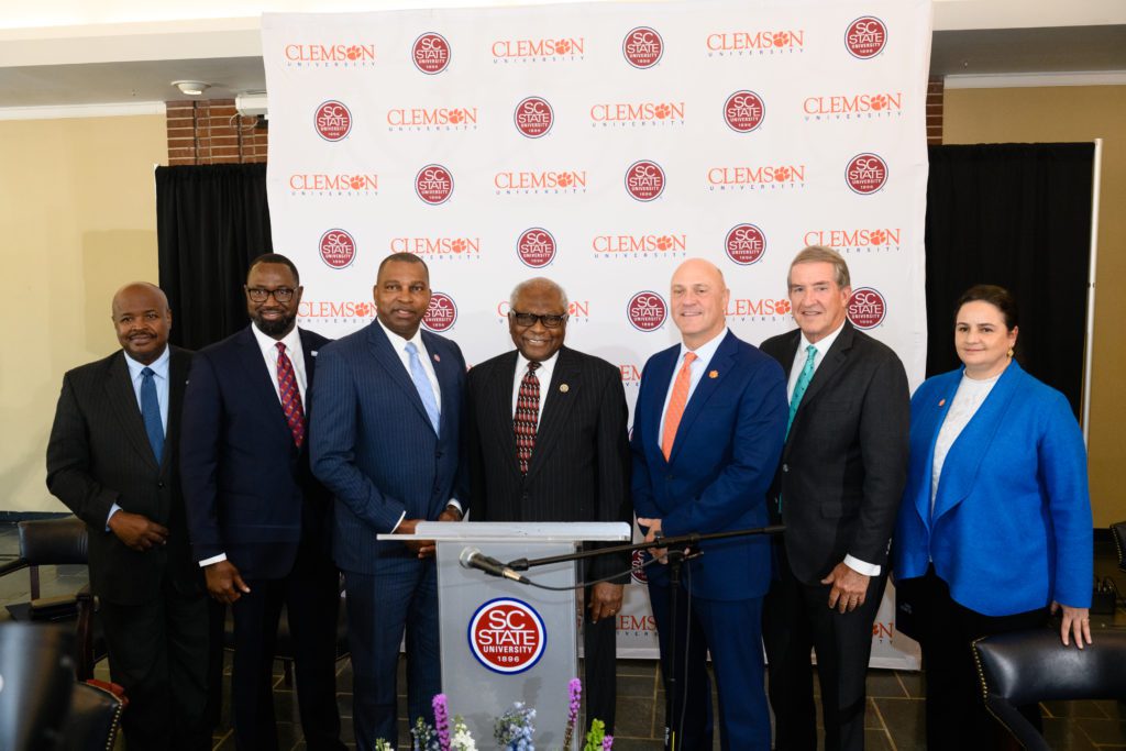 Dignitaries from South Carolina State University, Clemson University, the state of South Carolina and U.S. Congress stand in front of a banner with Clemson and S.C. State logos.