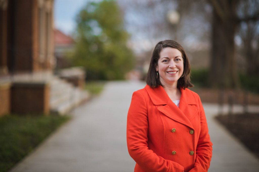 Bridget Trogden, associate dean for engagement and general education division of undergraduate studies, professor in the department of engineering and science education wears an orange blazer and stands on campus