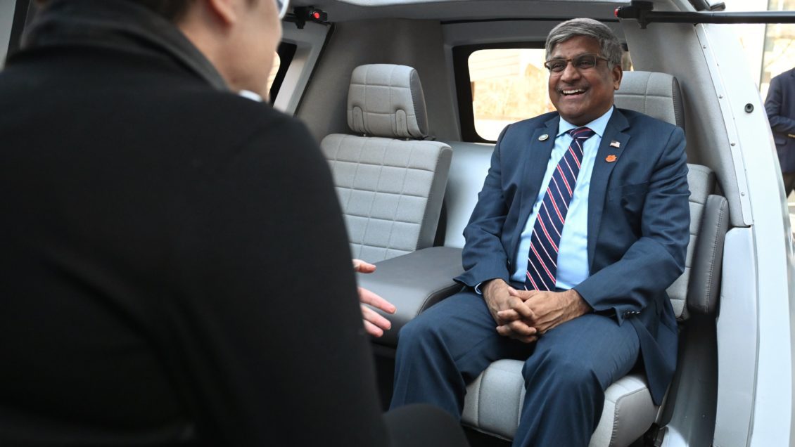 The NSF director is sitting inside an electric vehicle at the CU-ICAR campus.