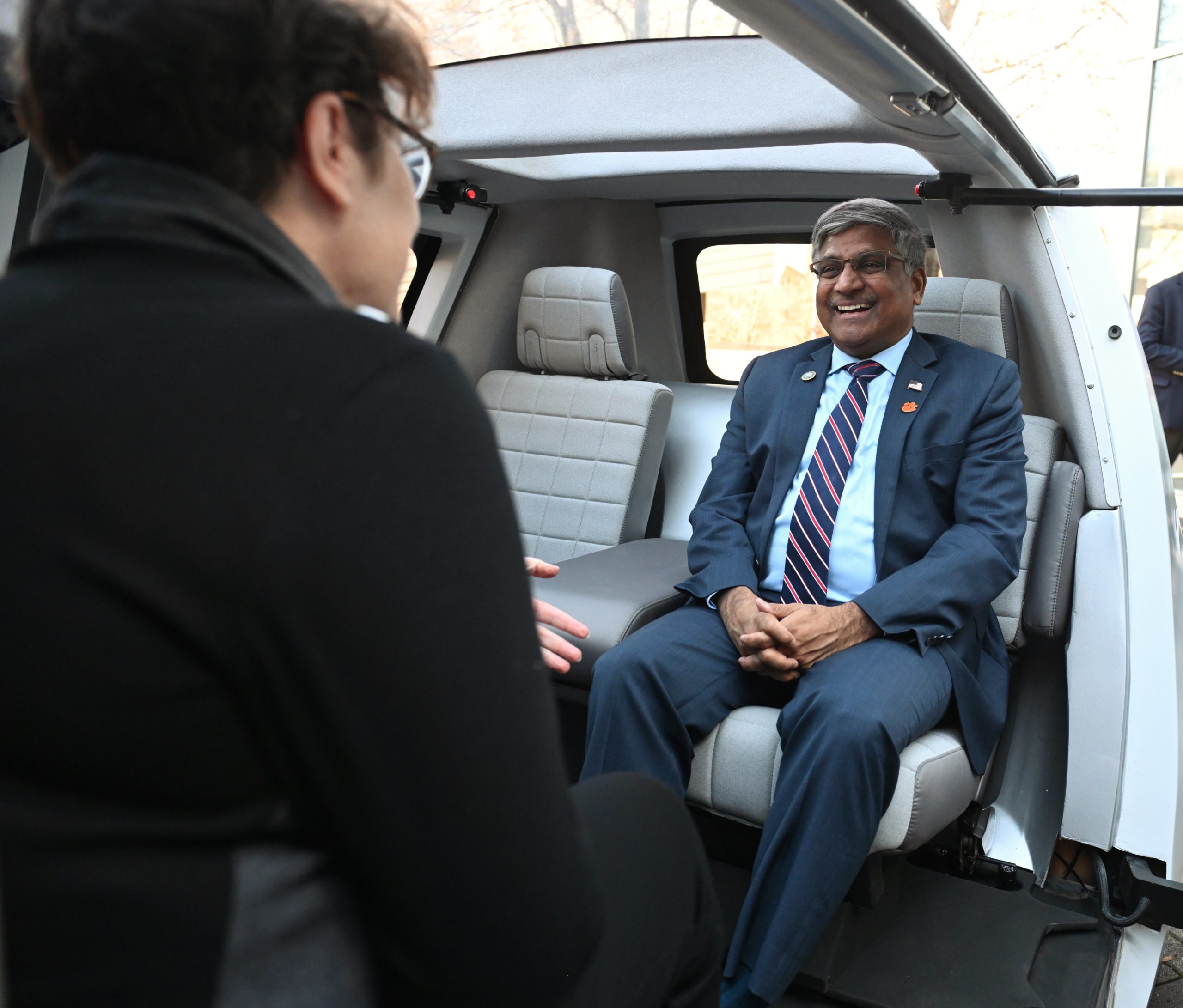 The NSF director is sitting inside an electric vehicle at the CU-ICAR campus.