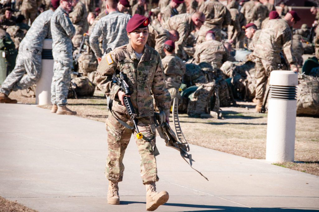 A woman wearing a U.S. Army uniform carries service weaponry. 