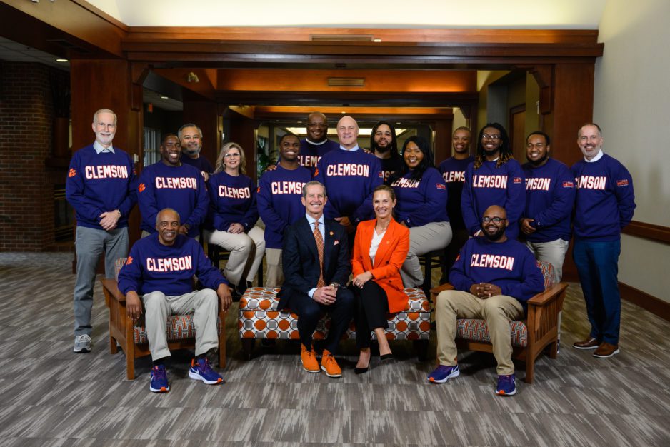 The Richardsons sitting in front of a group of people wearing purple Clemson sweatshirts