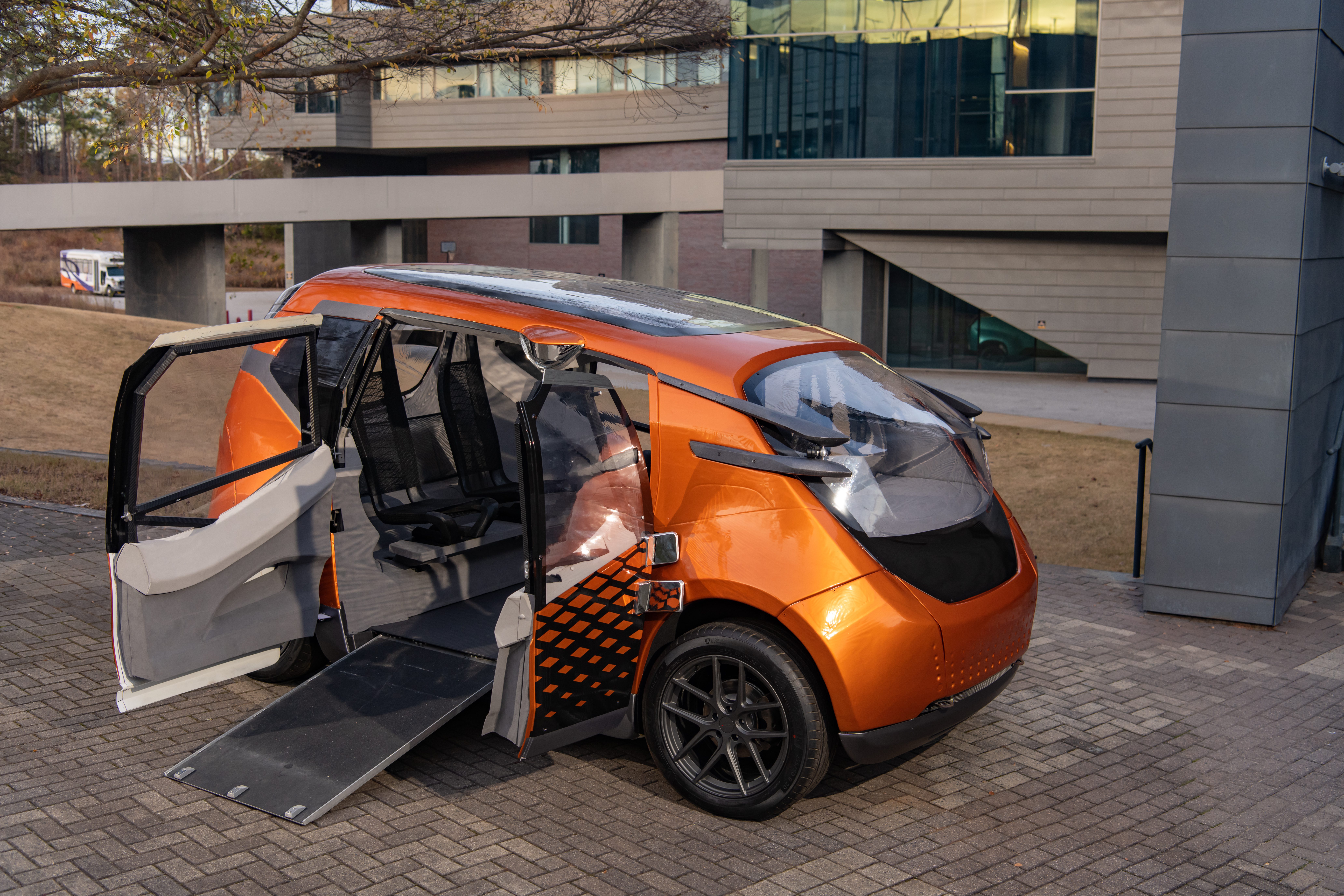 An orange car with its door open that accommodates a wheelchair ramp.