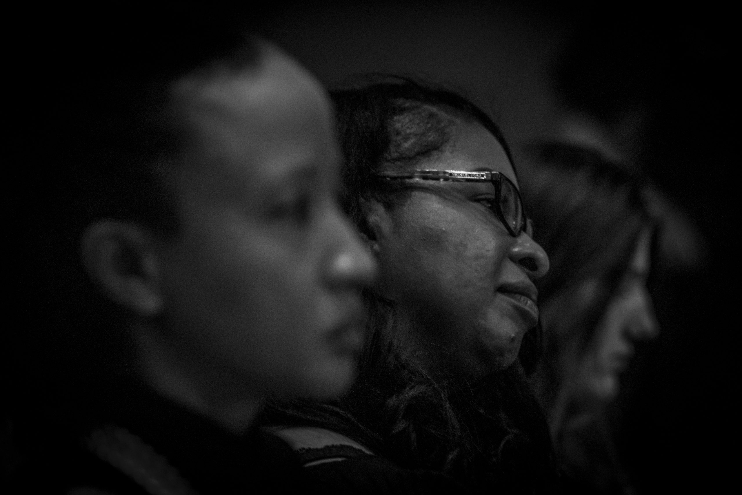The faces of three women, in profile and black and white, watching Yolanda King speak.