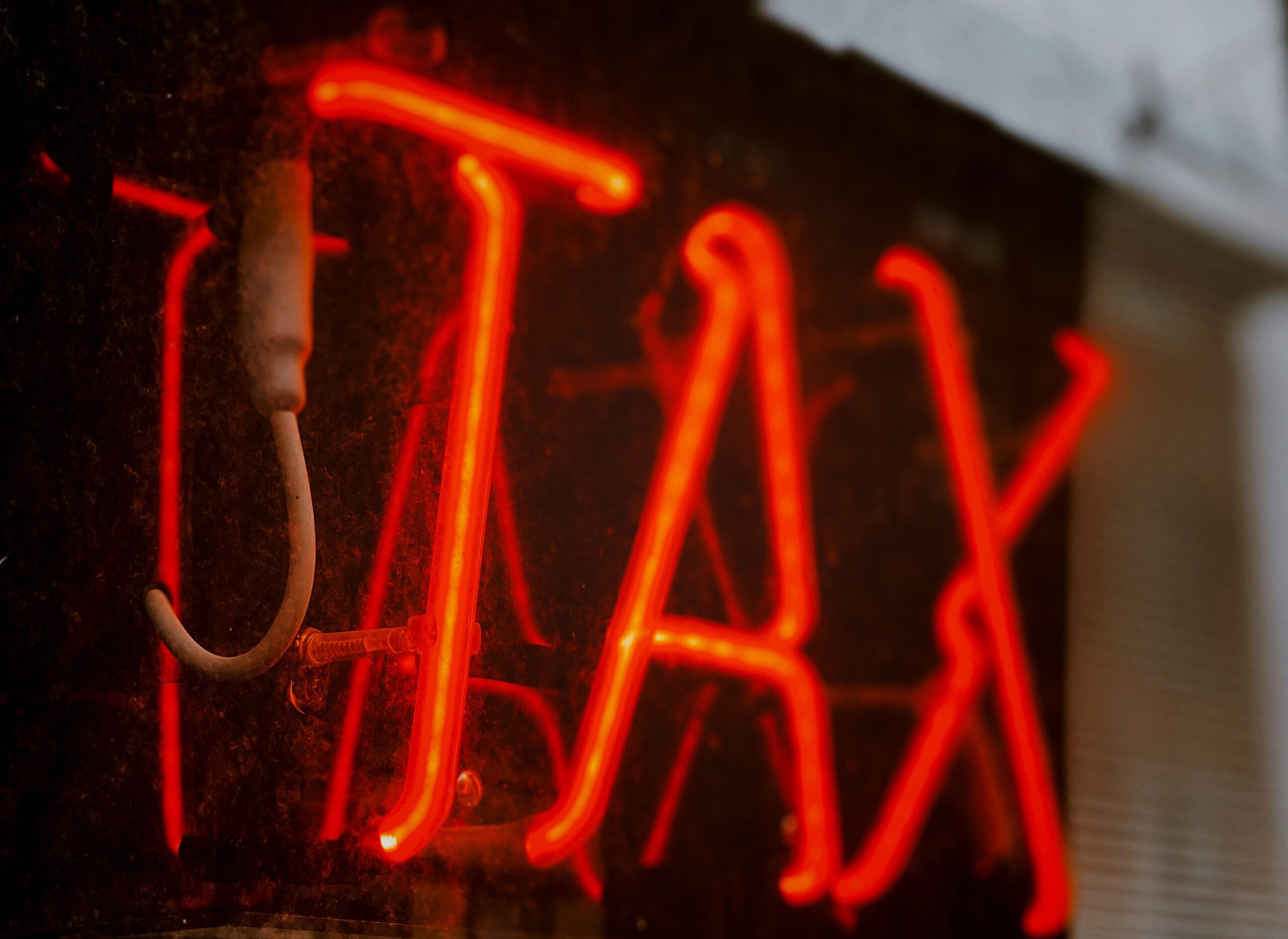 neon sign that spells tax, located inside a window of a business, drawing attention for 2022 tax filing season