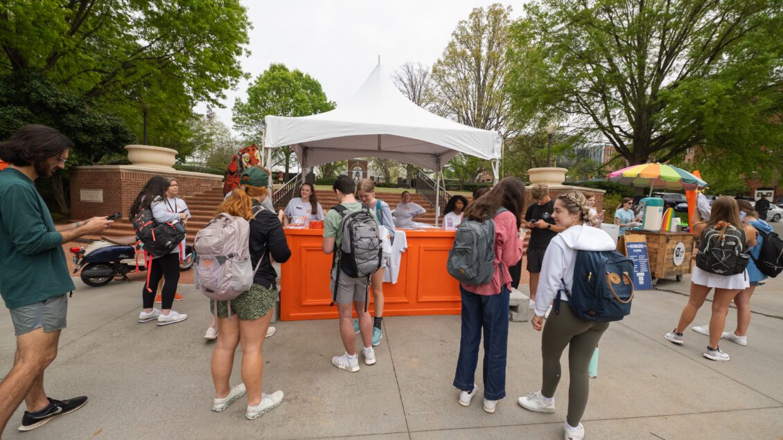 A diverse group of students stand in front of the 2023 Give Day booth.
