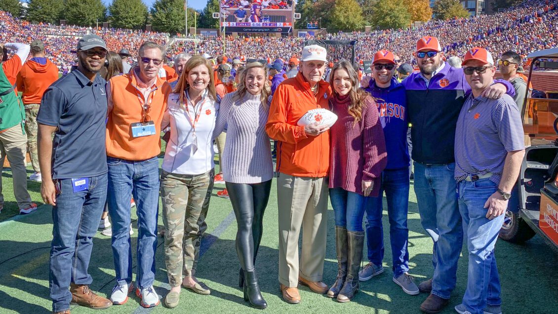 A group of people stand on the football field in Memorial Stadium, stands full of people behind them