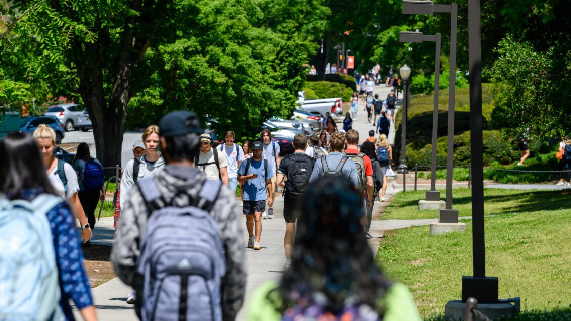 A diverse group of students walking outdoors on campus on a spring day. Photo for 2023 President's List.