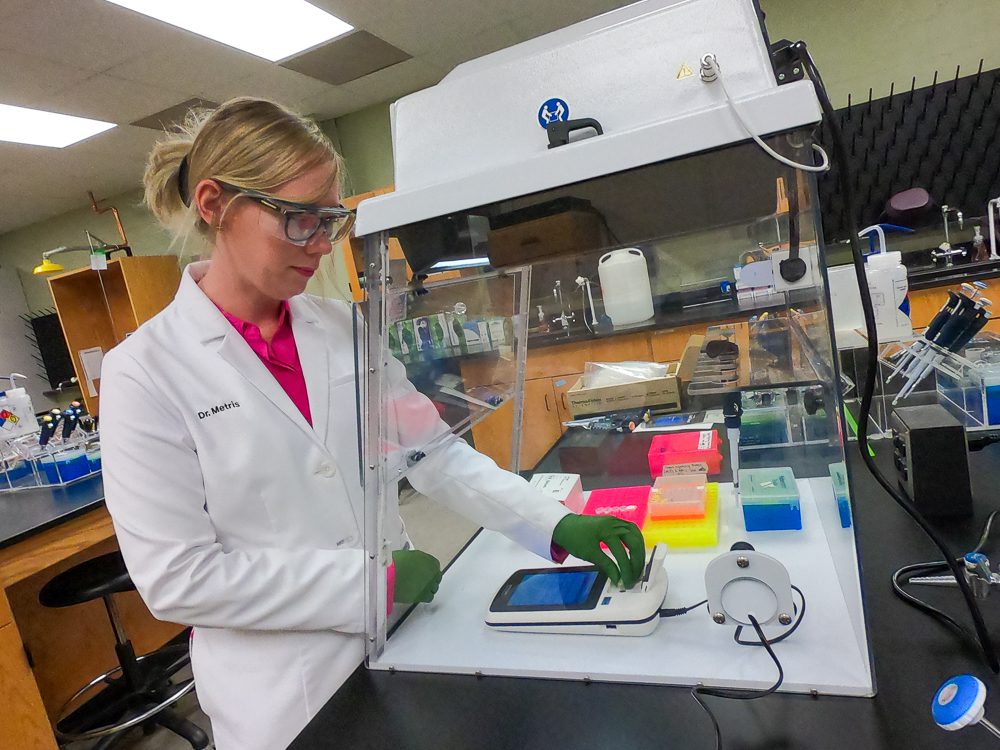 A woman wearing a white lab coat works in a lab at Clemson University.