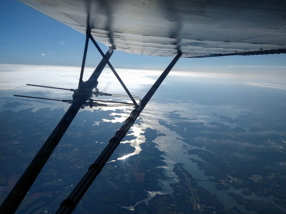 a probe to collect environmental DNA out of the air is mounted on the wing strut of an airplane flying over Lake Hartwell.