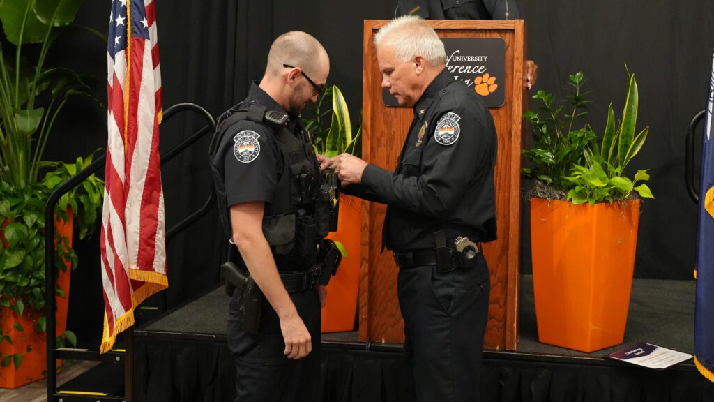 CUPD Officer Matthews has a pin added to his uniform by Chief Greg Mullen.