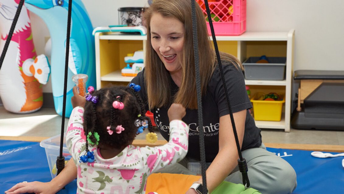 Woman (Elizabeth Timmons) works with a child at the Meyer Center for Special Children