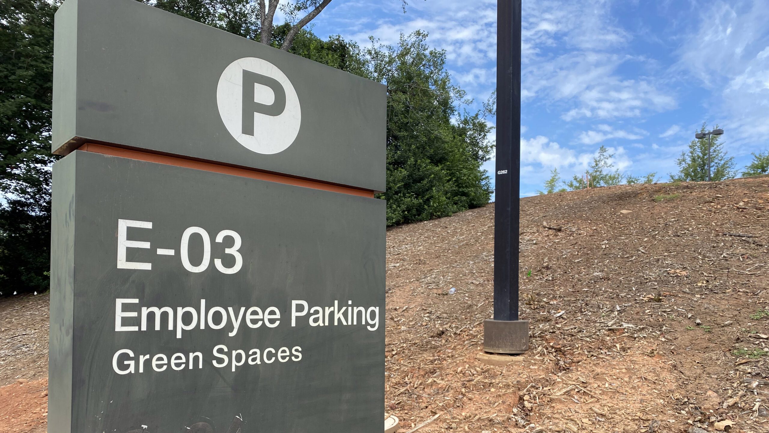 A parking sign reading "E-03 Employee Parking Green Spaces"