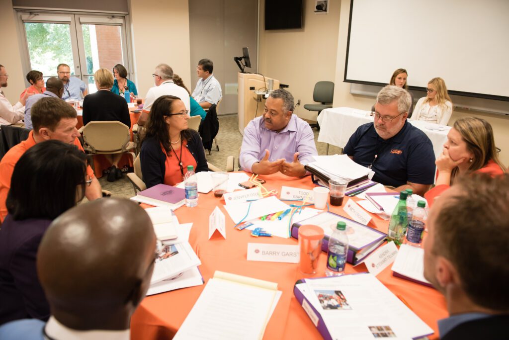 A group of leaders study the art of leadership while sitting at a table discussing options. 