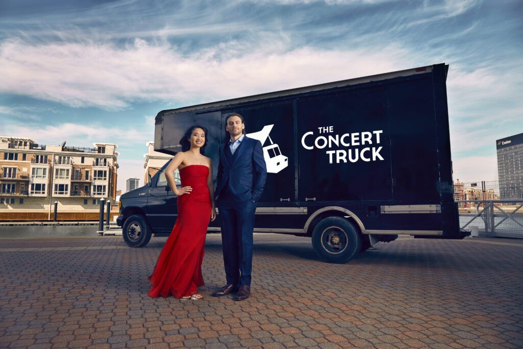 Susan Zhang and Nick Luby stand in front of The Concert Truck on a city street.