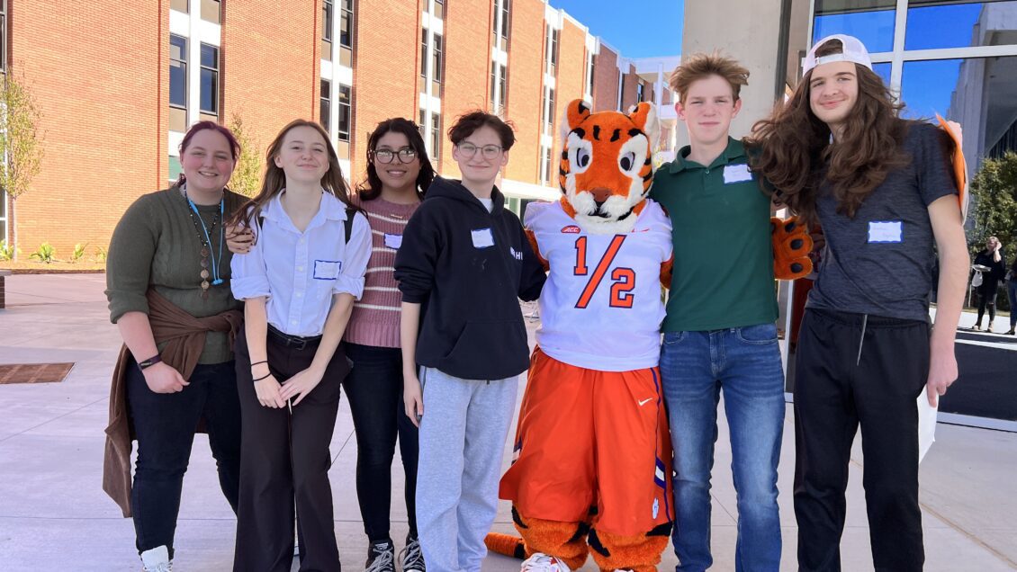 A group of high school students pose with The Tiger Cub outside of Humanities Hall on a sunny October morning.