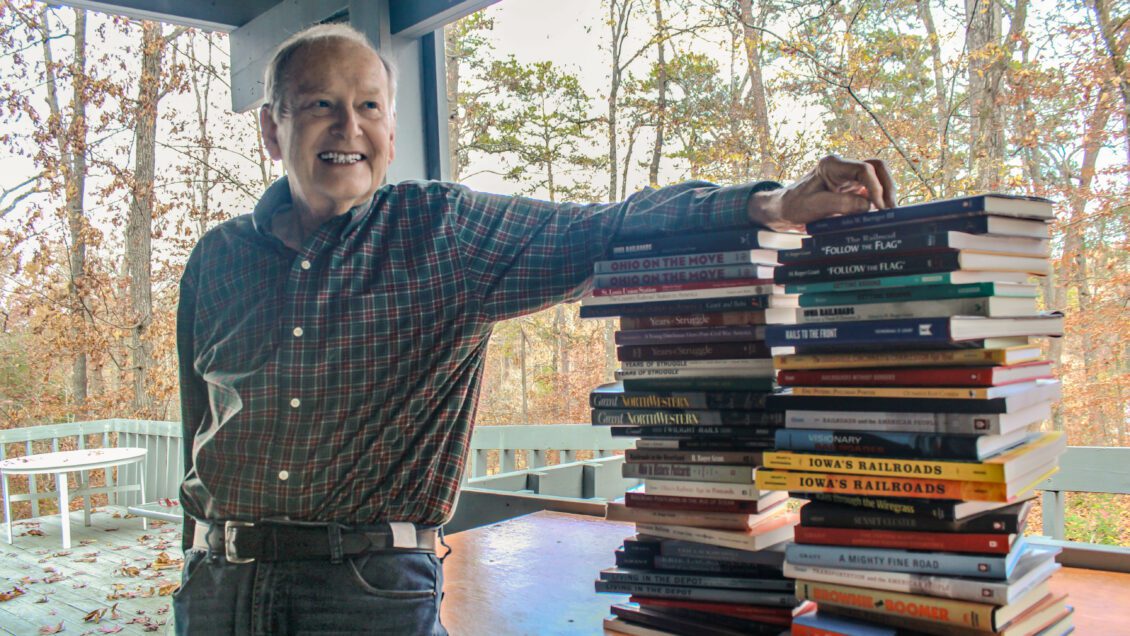 Roger Grant leans an arm onto a stack of books he's written, of which there are 40 in all.