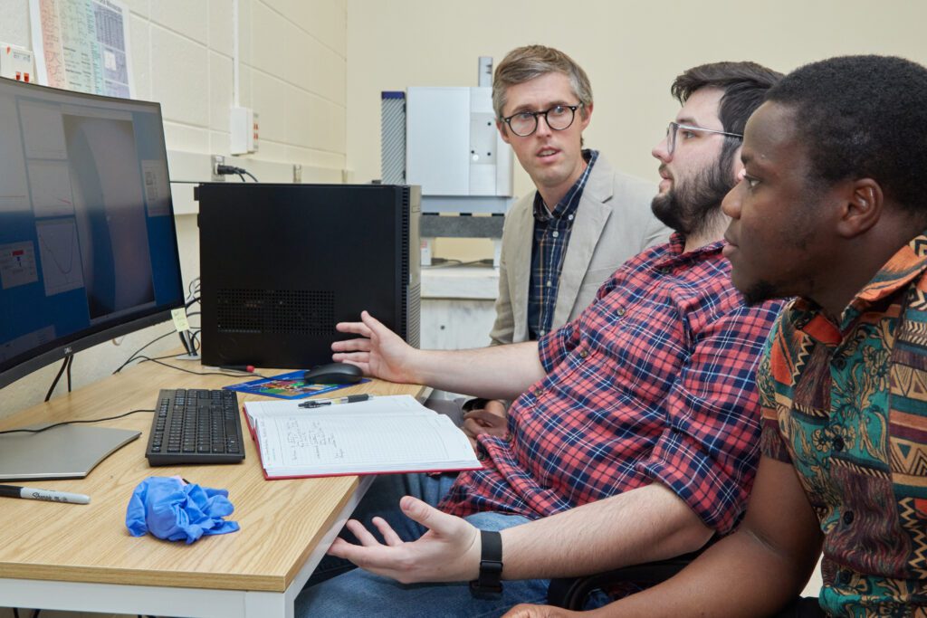  Department of Chemistry Assistant Professor David Jacobson (left with suit jacket) talks about research that could help find a therapeutic for diabetes insidious, a rare disease.