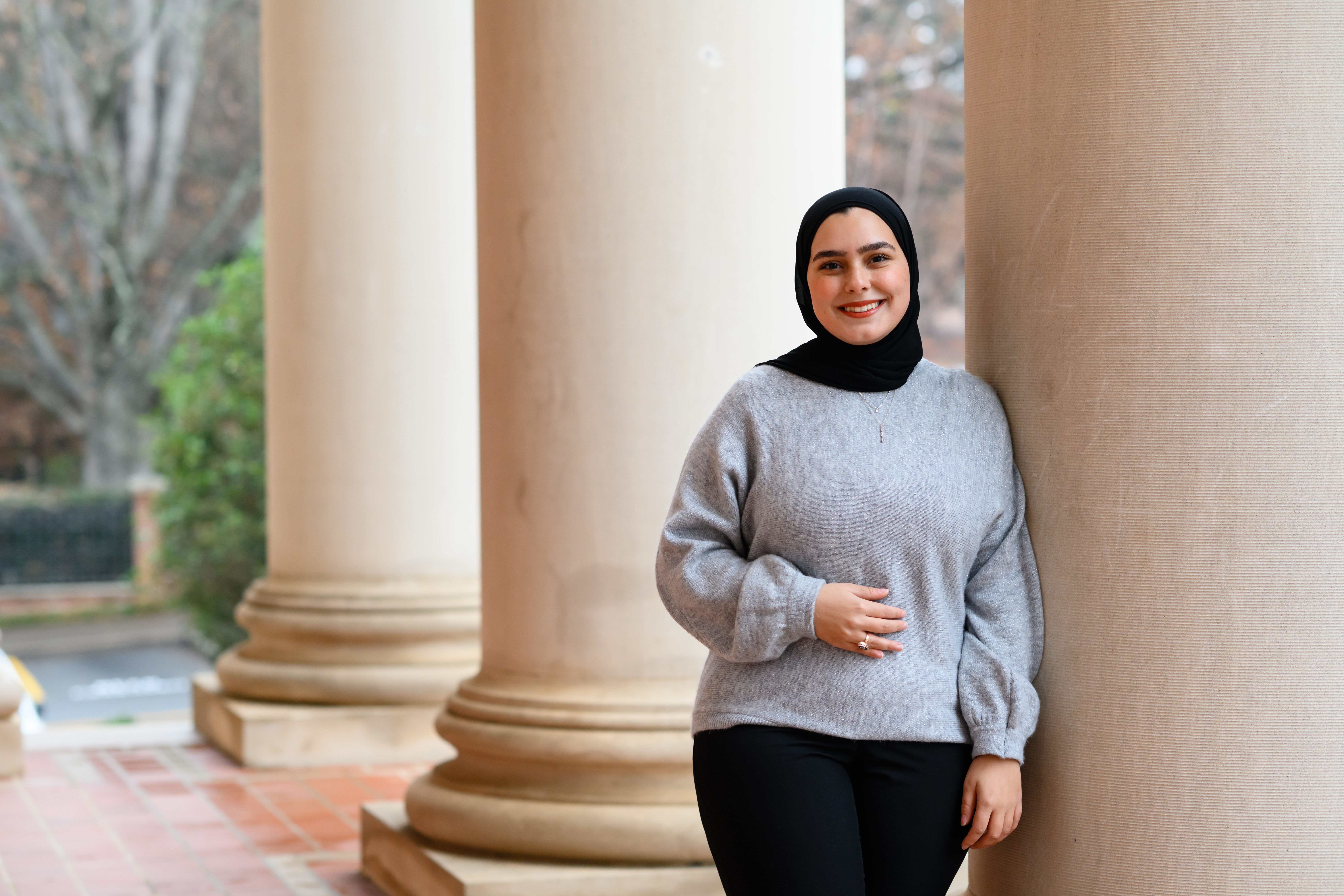 Rund Abdelnabi poses for a picture on a rainy day at a column at Sikes Hall.